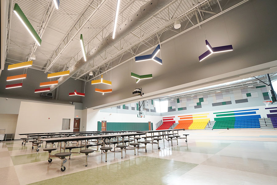 led light fixtures of varying shapes and rainbow colors hanging in cafeteria